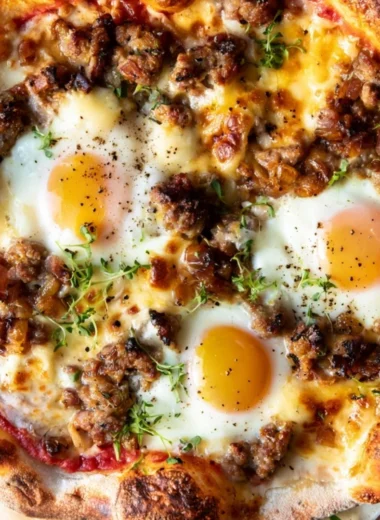 A delicious sausage breakfast pizza topped with eggs and cheese for a perfect morning meal