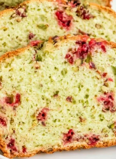 Cozy Cranberry Pistachio Bread fresh out of the oven, topped with cranberries and pistachios.