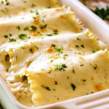 Creamy Chicken Alfredo Roll Ups topped with herbs and cheese