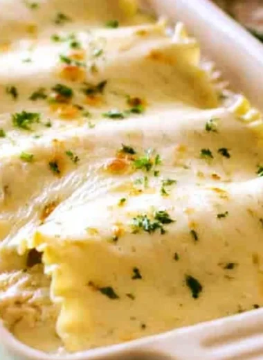 Creamy Chicken Alfredo Roll Ups topped with herbs and cheese