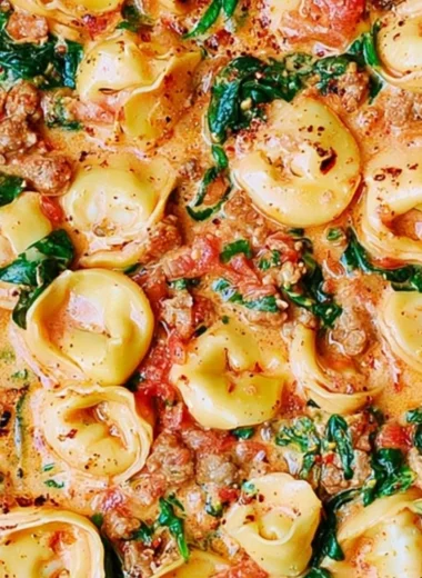 Creamy tortellini with sausage, spinach, tomatoes, and mozzarella in a bowl.
