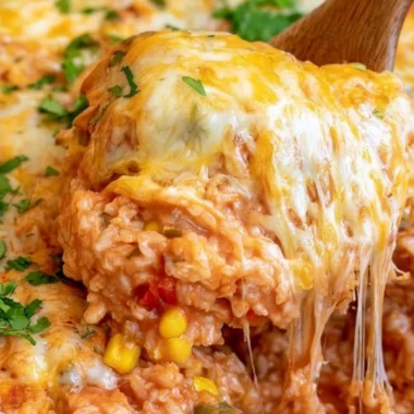 Delicious cheesy enchilada rice in a bowl, garnished with fresh herbs.