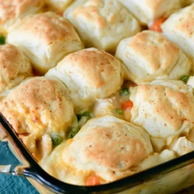 Cozy chicken pot pie topped with golden biscuits in a rustic dish.