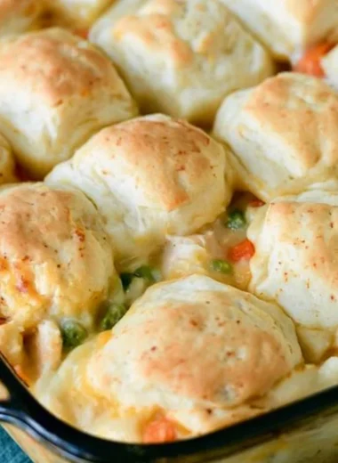 Cozy chicken pot pie topped with golden biscuits in a rustic dish.