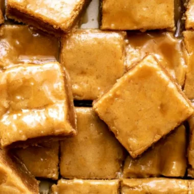 Delicious maple blondies topped with a decadent maple glaze on a rustic table.