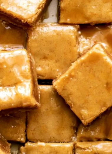 Delicious maple blondies topped with a decadent maple glaze on a rustic table.