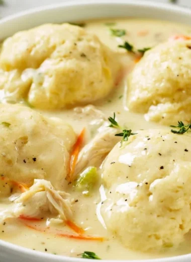 Bowl of homemade chicken and dumplings with fresh herbs on top