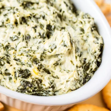 Easy hot spinach dip served in a bowl with tortilla chips around it.