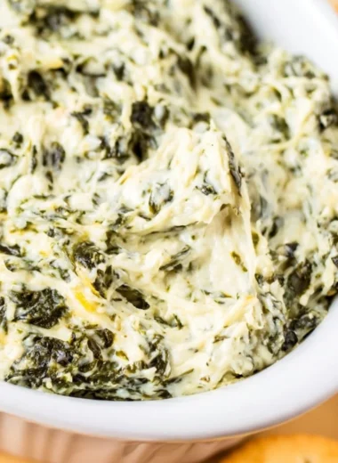 Easy hot spinach dip served in a bowl with tortilla chips around it.