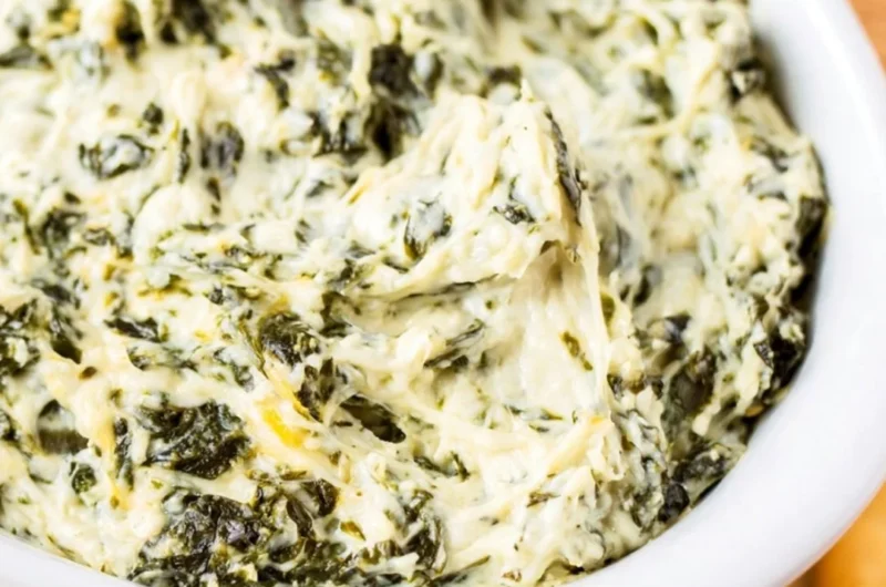 Easy hot spinach dip served in a bowl with tortilla chips around it.