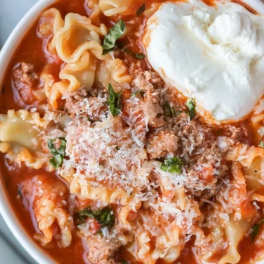 Delicious and healthy lasagna soup in a bowl topped with cheese and herbs