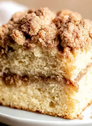 Sour Cream Coffee Cake topped with cinnamon and served on a plate